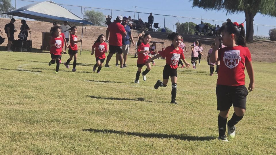 Yuma United players running across the field during a game.